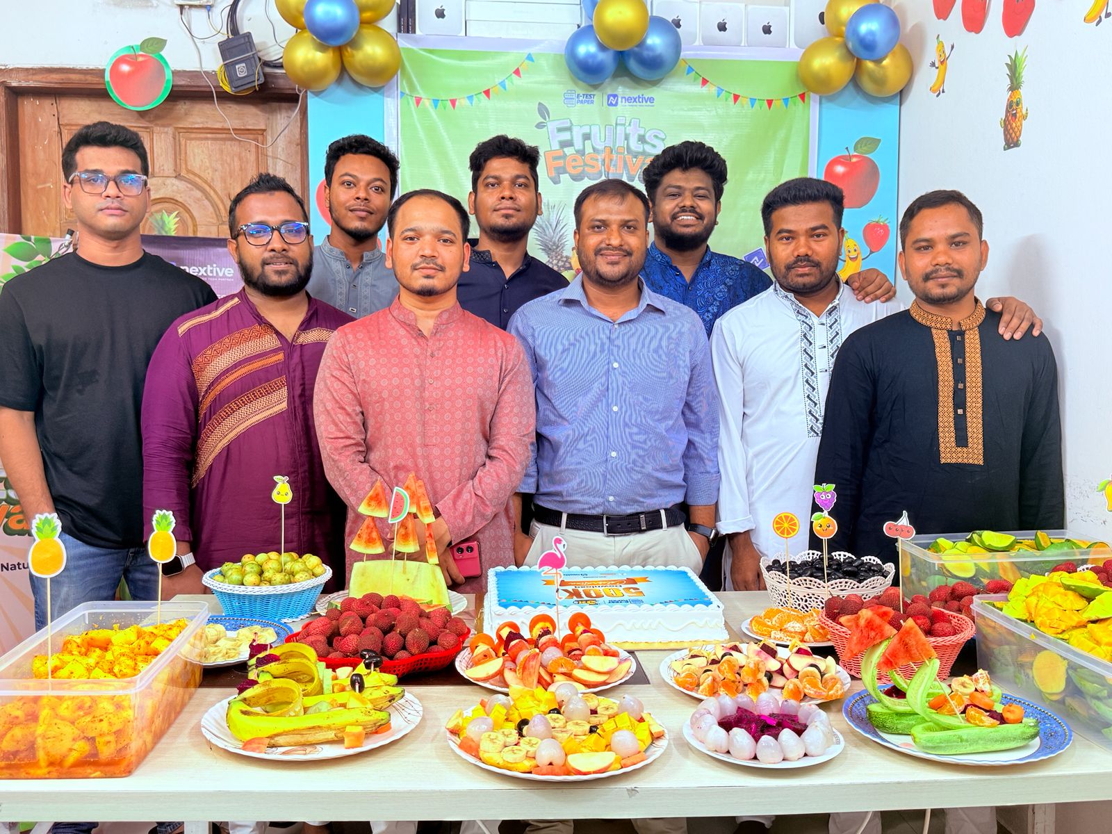 Team celebrating Fruits Festival with cake and fruit spread